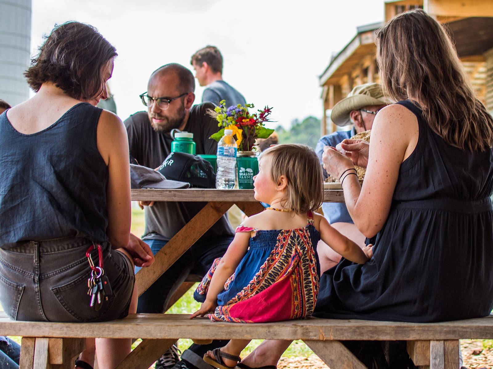Shalom Farms | Small girl looking at woman beside her at a picnic table