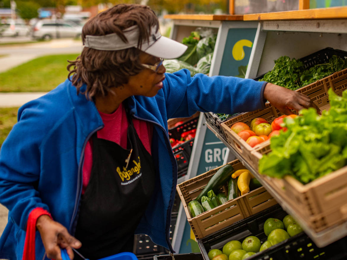 Shalom Farms | Woman reaching for produce at market
