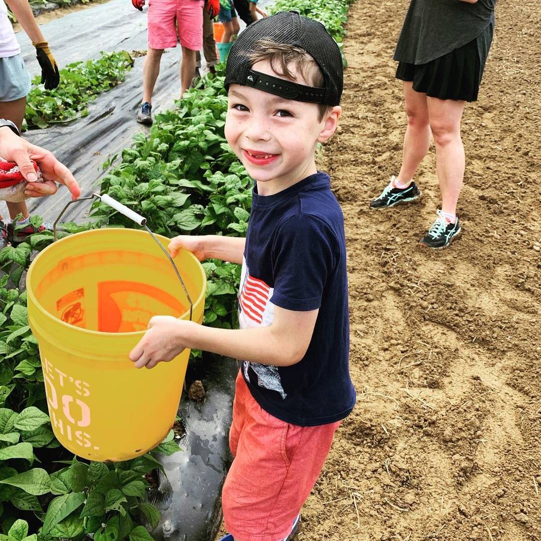 Shalom Farms | young child with bucket at farm